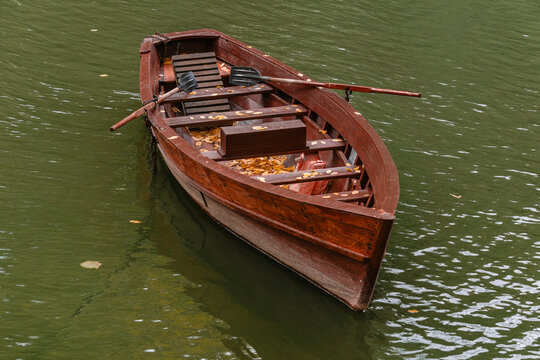 Wooden rowboat with oars on water
