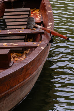 Wooden rowboat with oar on rippling water