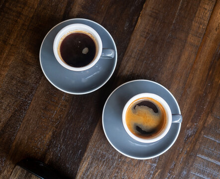 Two Grey Cups of Coffee with Black Coffee and Espresso with Crema on Dark Wooden Table