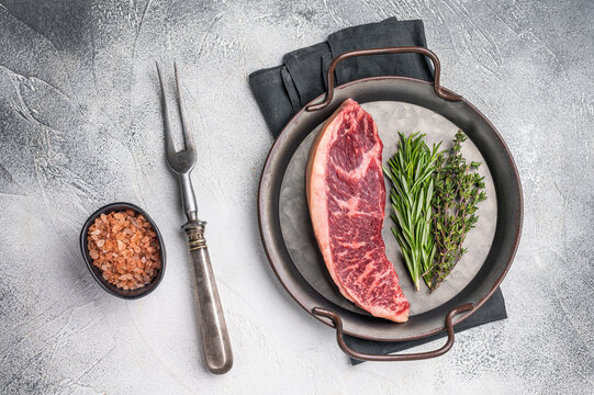 Raw rump cap steak, beef meat, showcasing its rich color and marbling.  grey background. top view