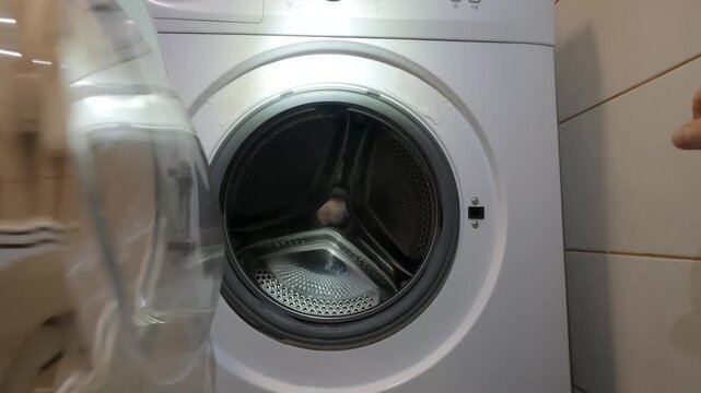 Hand Closing Door Of Empty Washing Machine In Bathroom