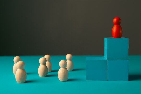 Leadership concept. The red leader stands on top of the podium among the other figures.