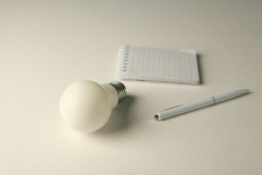 Lightbulb and notepad on white background, idea concept.
