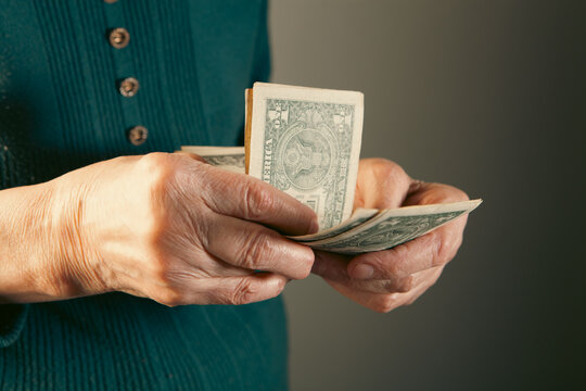 Elderly woman counting money, closeup of hands counting dollars