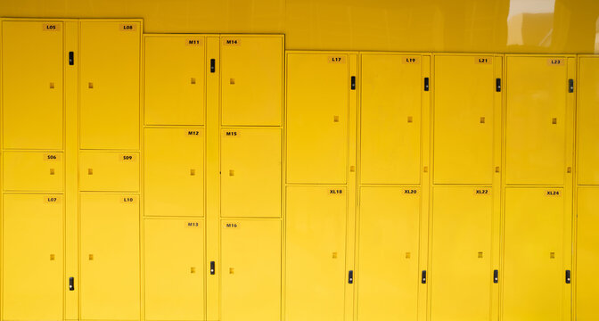 Bright yellow self service storage lockers arranged in a public facility for tourists and commuters, providing secure temporary luggage, parcel and personal item storage during travel and transit