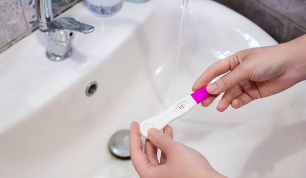 Hands of woman holding a positive pregnancy test result stick 