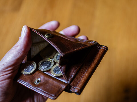 Leather wallet with British coins in a mans hand.