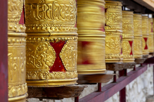 Row of golden prayer wheels with embossed mantras at Yuru Monastery, Ladakh, Lamayuru, India