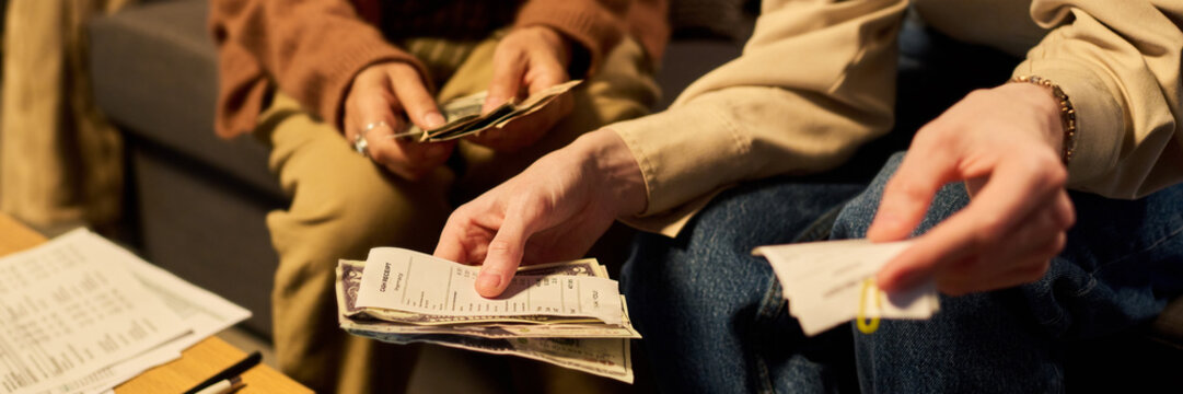 Header of cropped hands of young adult Caucasian people holding cash receipts and money while calculating home expenses. Concept of personal budget planning and financial management