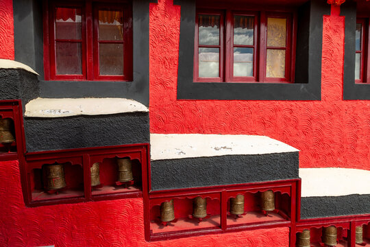 Row of prayer wheels set in a red wall at Thiksey monastery, Ladakh, Thiksey, India