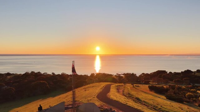 Kingscote, Kangaroo Island, South Australia &ndash; 4K Aerial Drone View of Sunrise over Reeves Point, Flagstaff Hill, Australian flag, Coastal Hills, calm ocean waters, glowing sea reflections