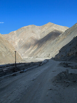 Mountainous road in a barren and arid landscape under clear blue sky