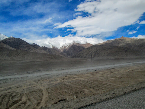 Vast mountainous landscape under a clear blue sky with scattered clouds