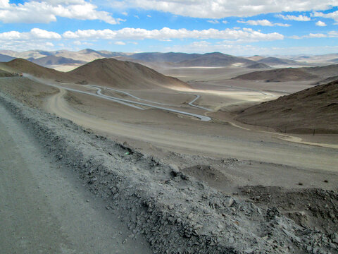 Winding road in a vast arid desert landscape under a clear sky