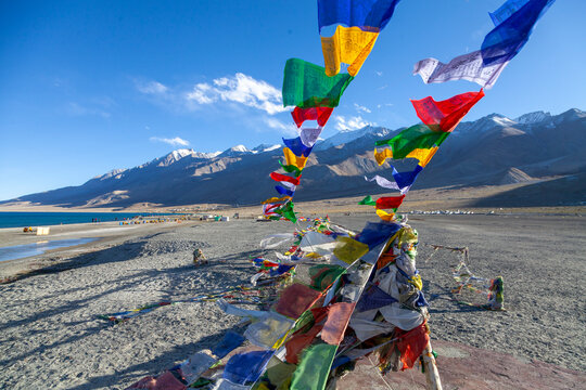 Colorful prayer flags fluttering on the shore of Pangong Lake with snowy mountains, Ladakh, Merak, India