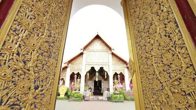 Beautiful Lanna architectural details of the entrance gate and golden gable at Wat Phra That Hariphunchai in Lamphun, Thailand.