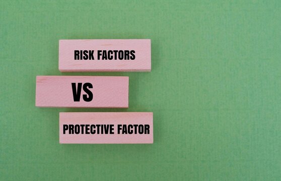  RISK FACTORS VS PROTECTIVE FACTOR text on wooden blocks against a green background. Concept of mental health, wellness, risk management, and decision making