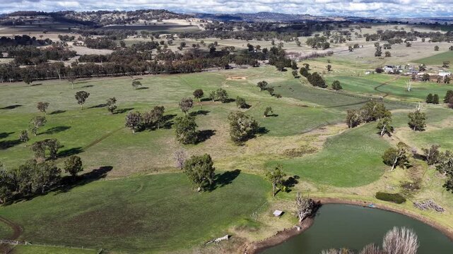 Aerial video moves over rural farmland at Swan Brooke, revealing open paddocks, cultivated fields, green pasture and the surrounding countryside in a broad overhead view.