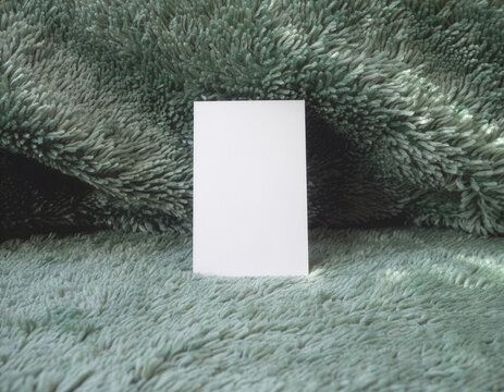 Blank white business card mockup on a plush green cushion