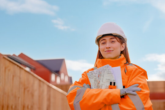 Young female construction engineer wearing personal protective equipment safety helmet   at a construction site. She works with technical plans Concept of women in the construction industry
