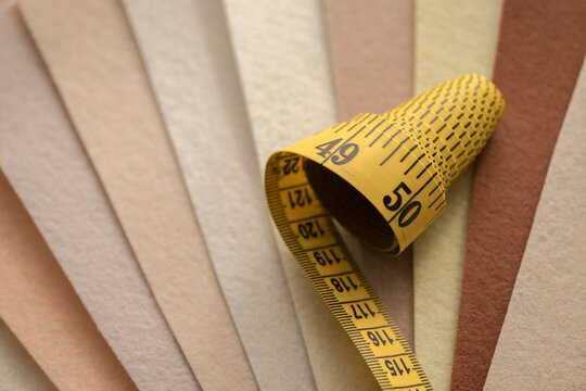 Measuring tape curling across neutral fabric swatches for textile design