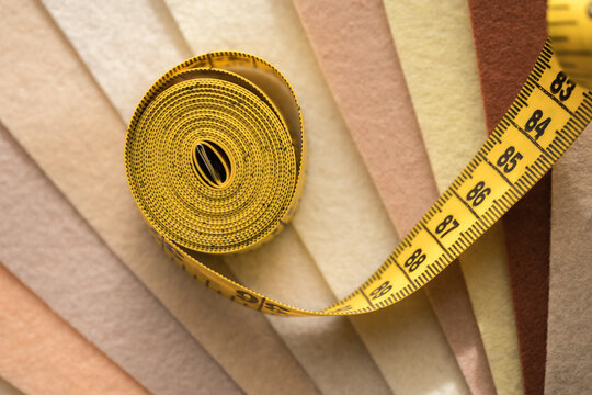 Yellow measuring tape curling over colorful felt fabric swatches