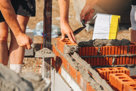Workers lay bricks and mortar during a building project at a construction site