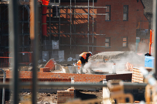 Construction worker pours concrete at a building site during the day