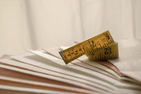 Yellow measuring tape on layered fabric swatches for sewing and textile design