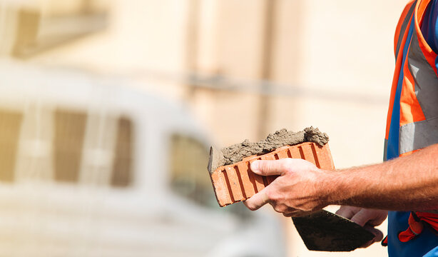Construction worker holding a clay brick at a building site