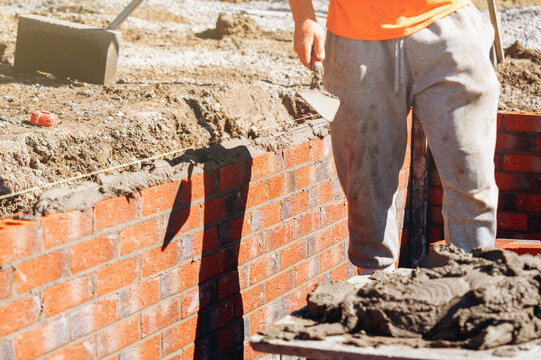 Worker applies mortar to a brick wall at a construction site