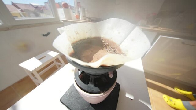Steam rising from a pour over coffee dripper in bright window light