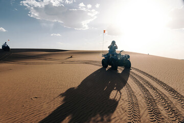 Traveler riding an all-terrain vehicle through the sandy dunes of erg chebbi, merzouga, morocco, enjoying adventure © Manuel