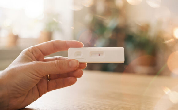 Woman holding a negative pregnancy test in a bright home interior representing health diagnostics fertility testing and family planning