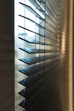 Close-Up of Dark Horizontal Window Blinds with Soft Natural Light and Warm Shadows
