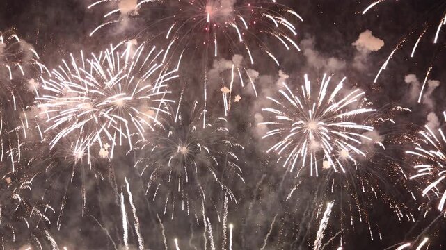 Bright white and golden fireworks exploding in dark night sky, representing grand celebration, New Year event, anniversary party, festival, Independence Day, and holiday background concept