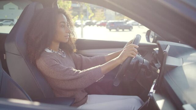 Woman sits inside parked car holding steering wheel calmly