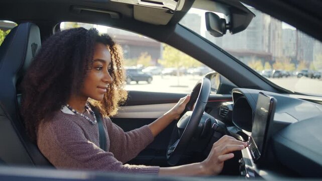 Woman uses touchscreen while sitting in driver seat of car