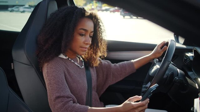 Woman reads sms on smartphone while holding steering wheel in car