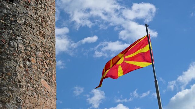Waving Macedonian flag next to a historic stone tower