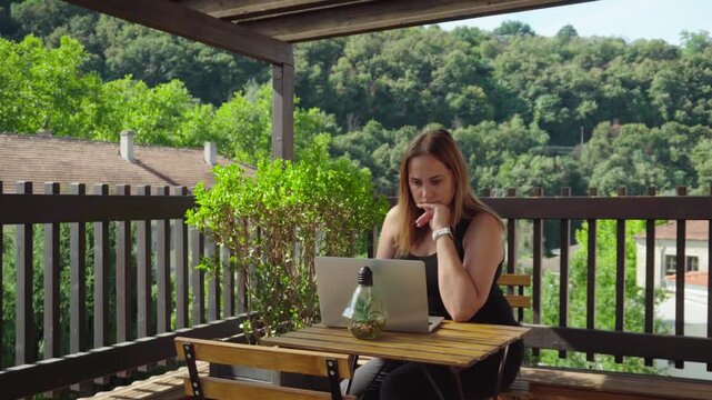 Focused Businesswoman Reviewing Work on Laptop at Outdoor Workspace