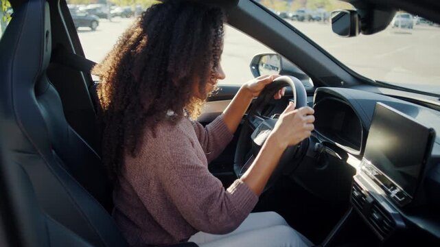 Excited woman admires new car from driver seat with smile