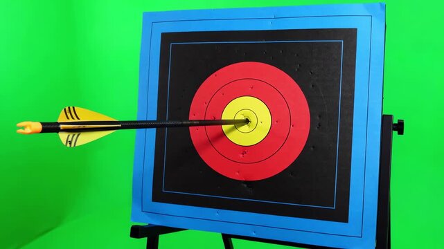 Close up shot of a carbon fiber arrow striking a red foam archery target isolated on a solid green screen background