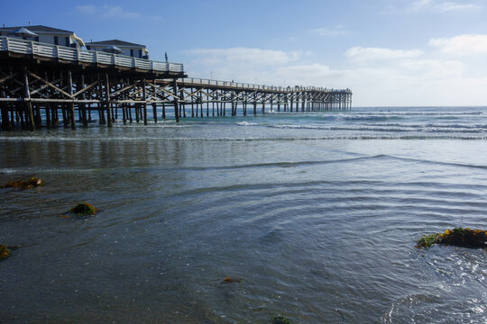 Crystal Pier in San Diego during low tide with gentle waves rolling onto the sand, Southern California