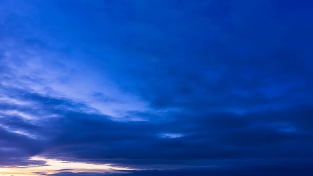 Deep blue clouds fill a wide open sky above a softly lit horizon line