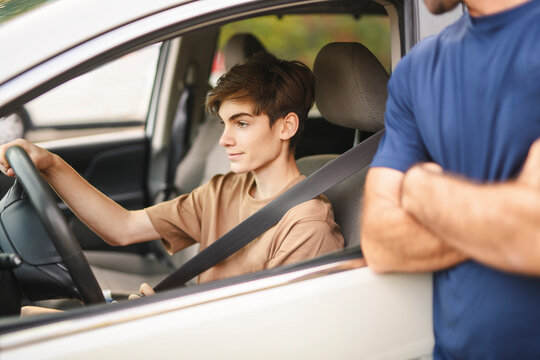 handsome father teaching teen son driving car