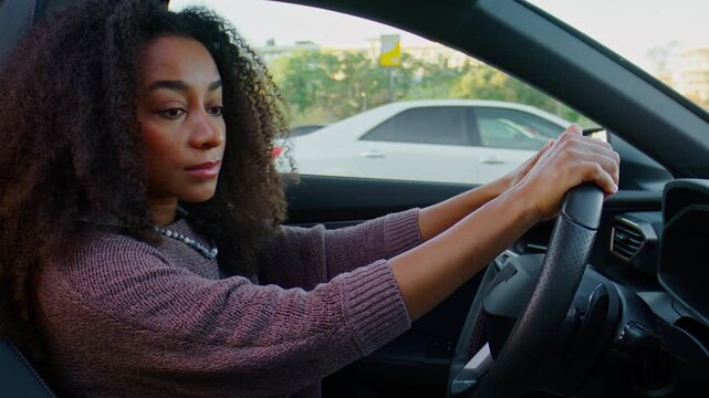 Woman with bouncy curls navigates bustling downtown road in car