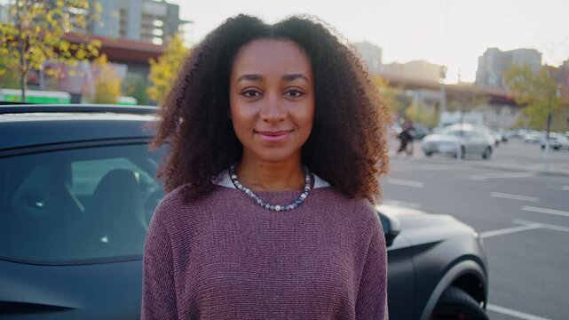 Smiling African American woman stands near car on parking lot