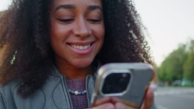 Black woman holds sleek smartphone and types personal message