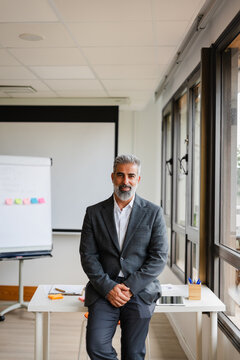 Handsome businessman leans on a desk